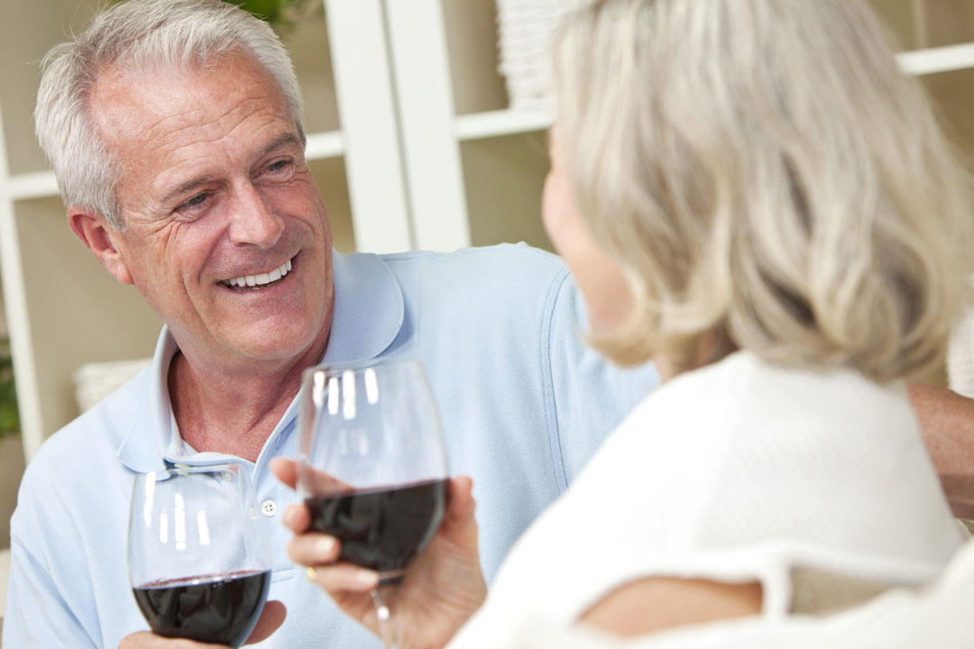Happy elderly couple enjoying wine together, smiling.